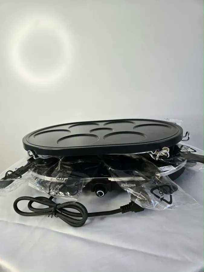 Raclette de la marque française Tristar en finition noire, plaque de cuisson supérieure amovible à alvéoles pour mini-crêpes
