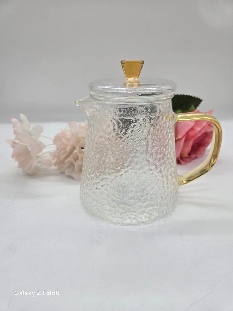 Théière en verre transparent à la texture martelée distinctive et anse polie dorée