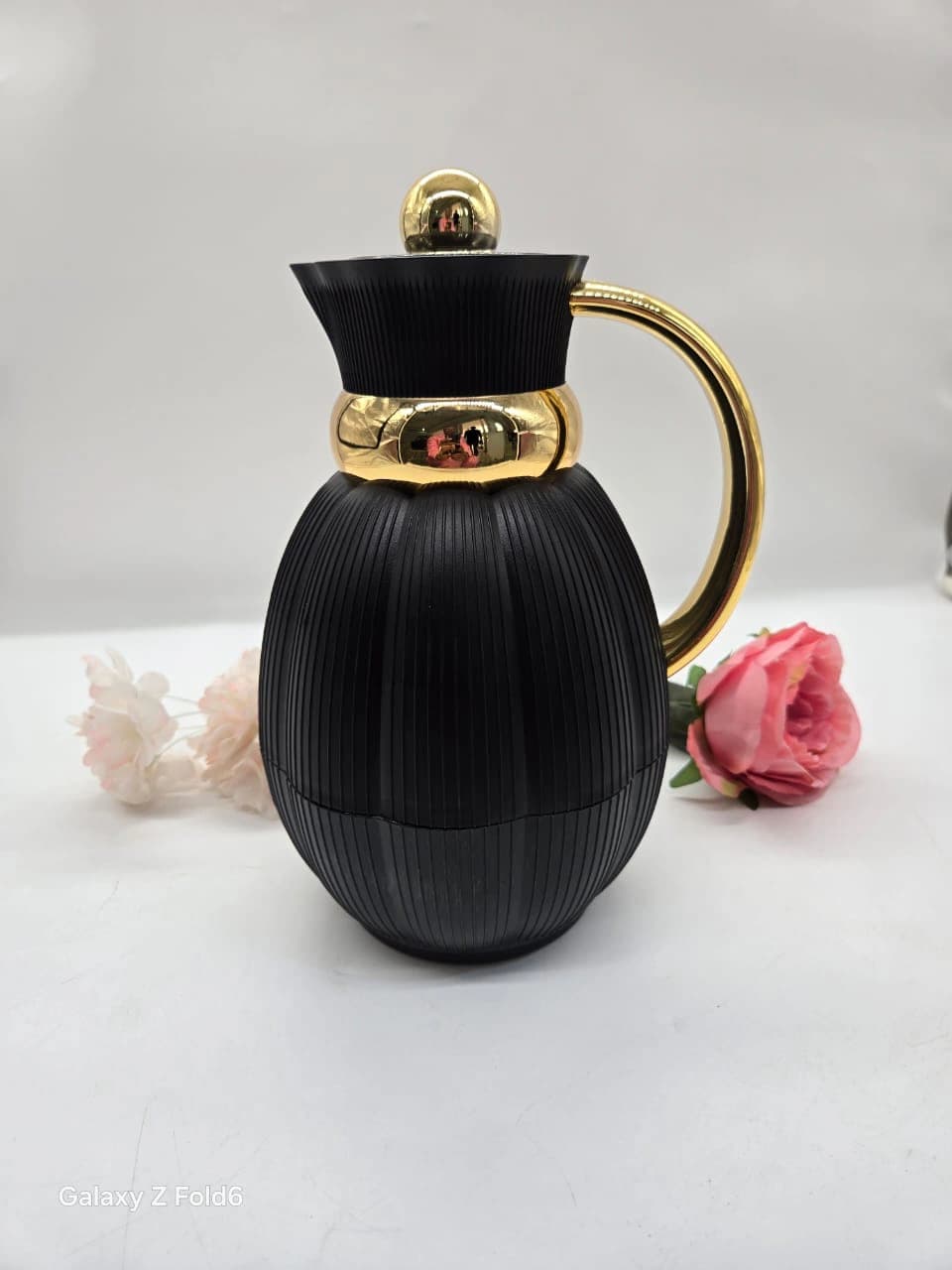 Thermos noire et dorée au corps côtelé et aux finitions dorées brillantes