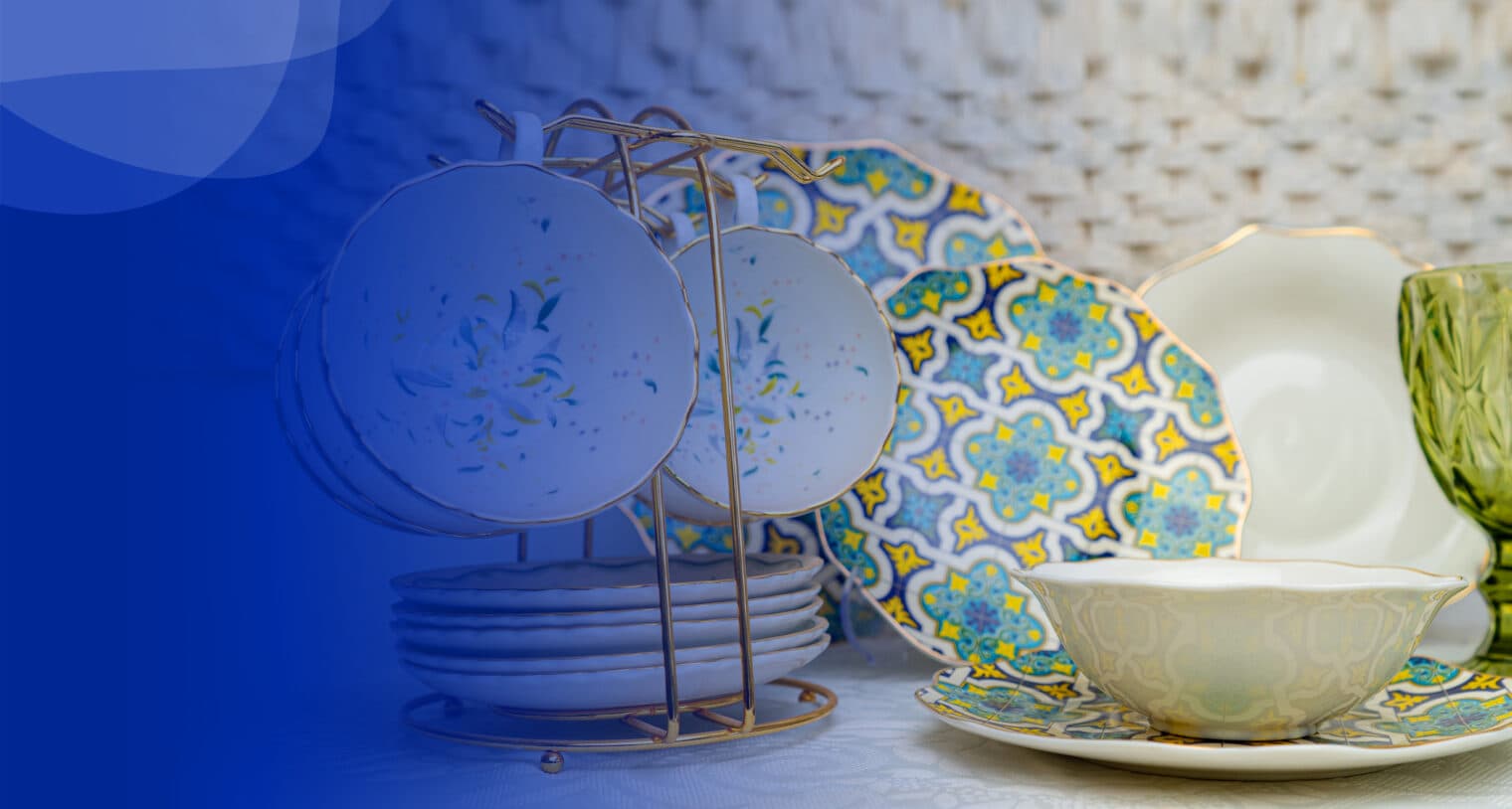 Service de table aux motifs bleus et jaunes sur un support doré, bols et verre vert.
